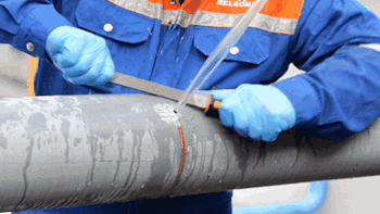 Man using handheld surface preparation tool on leaking pipe